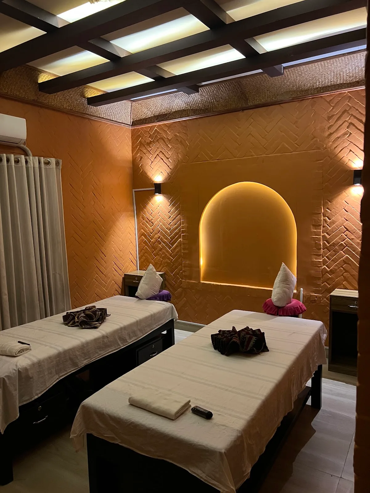Twin treatment room at Senses Spa with warm terracotta walls and arched alcove